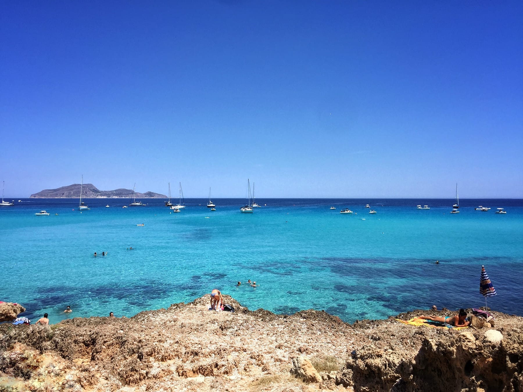 Cala Azzurra auf Favignana mit türkisfarbenem Wasser und Segelyachten vor der Küste