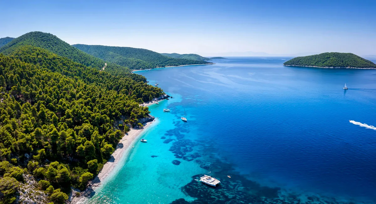 Kristallklares Wasser in den Sporaden mit Yachten vor anker in einer türkisblauen Bucht